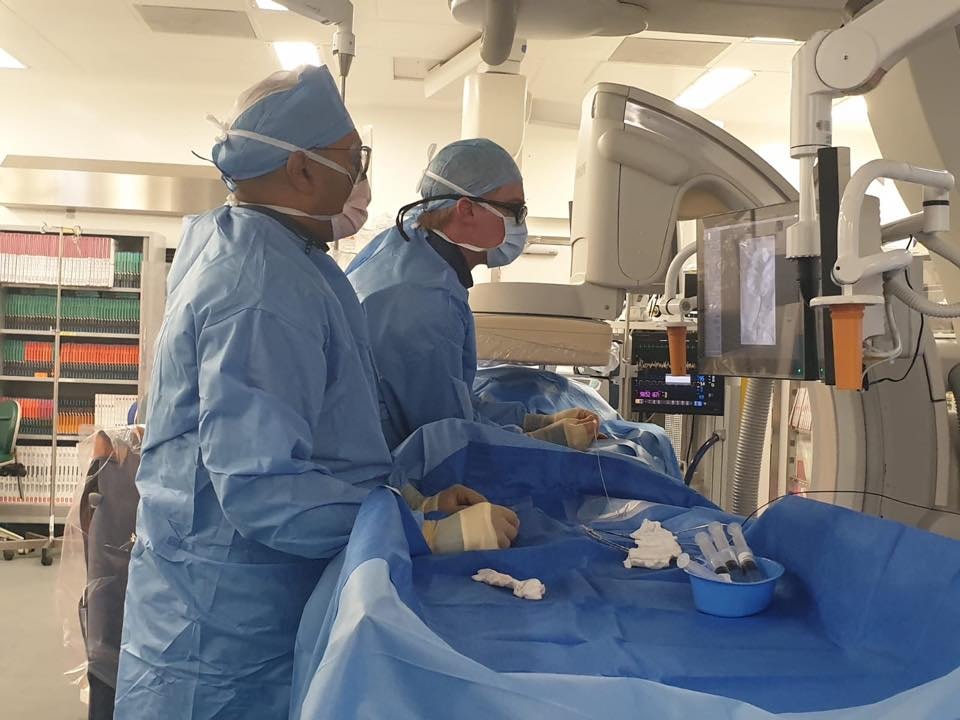 Vascular surgeons performing a minimally invasive pelvic vein embolisation procedure in an interventional suite